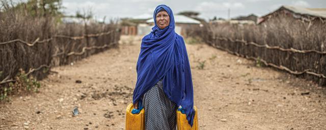 Ethiopian woman walking with two yellow jerrycans.